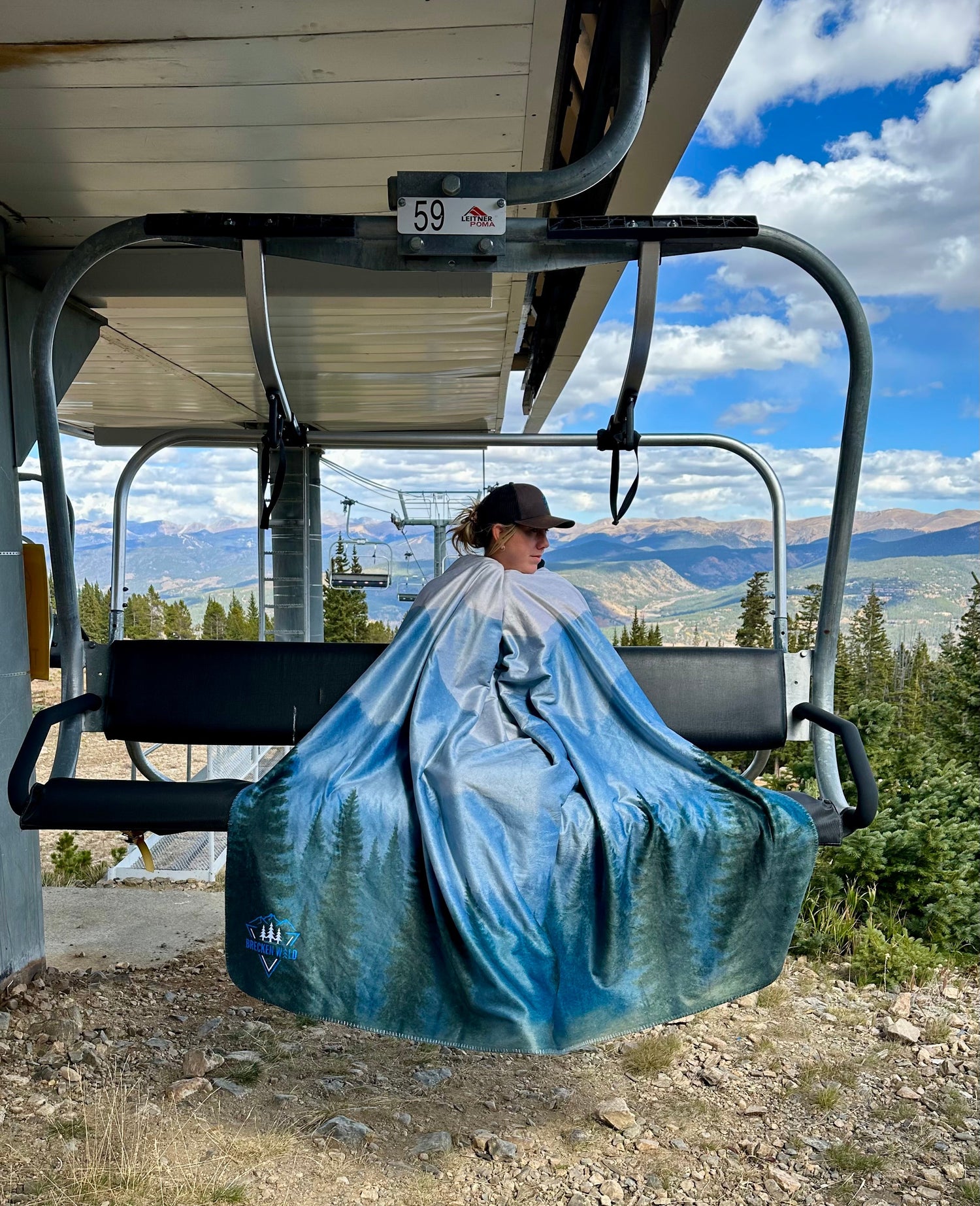 Girl sitting on chairlift at Breck wrapped in a nature art blanket